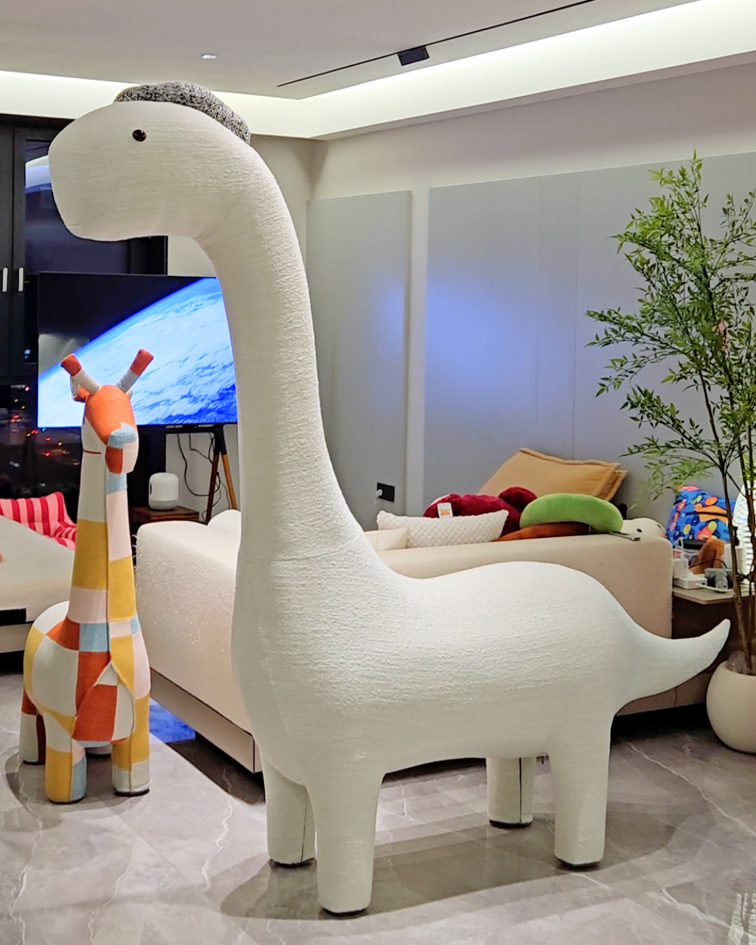 A giant dinosaur-shaped furniture piece in a living room setting, with a cat climbing on it and a bench for humans.
